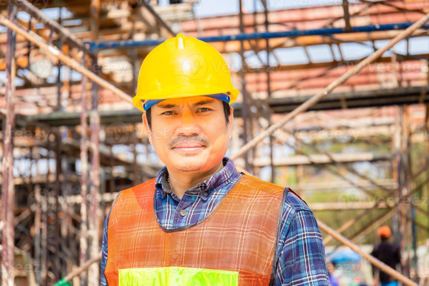 ingeniero hombre trabajador comprobando y planificando proyecto en el sitio de construcción, hombre sonriente con fondo borroso foto