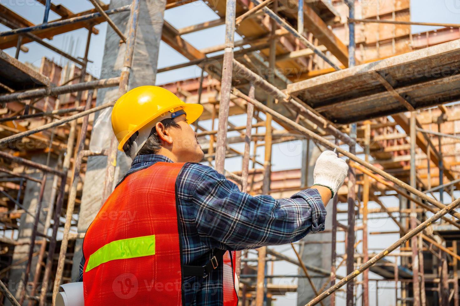 trabajador de capataz en casco con proyecto de planificación y comprobación de planos en el sitio de construcción foto