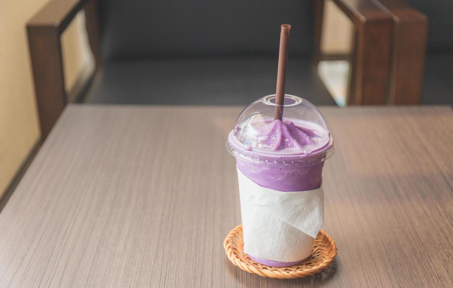 Iced blueberry smoothie cup on wood table in coffee shop photo