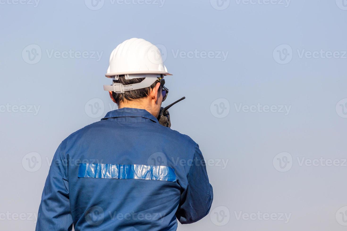 Foreman in hardhat and safety vest talks on two-way radio control loading containers box from cargo photo