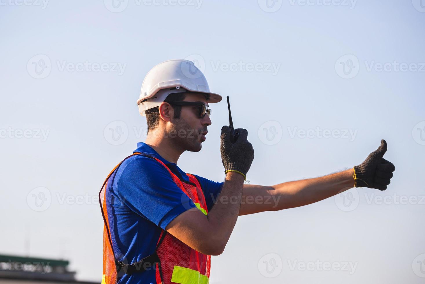 Factory worker man in hardhat talks on two-way radio with giving thumbs up, Foreman control loading containers box from cargo photo