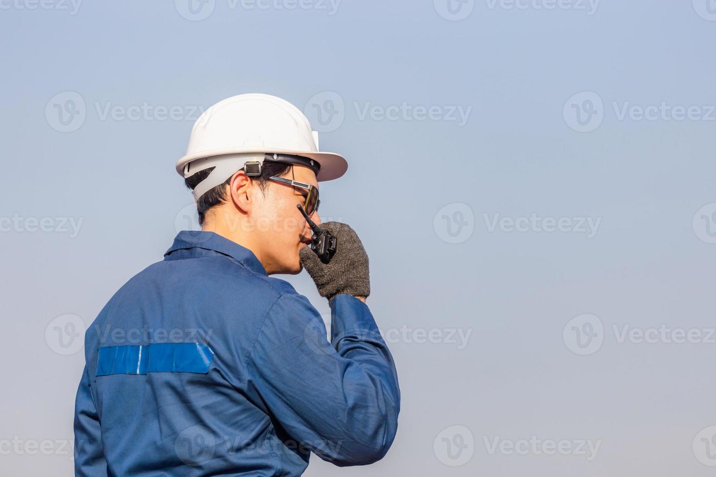Foreman in hardhat and safety vest talks on two-way radio control loading containers box from cargo photo