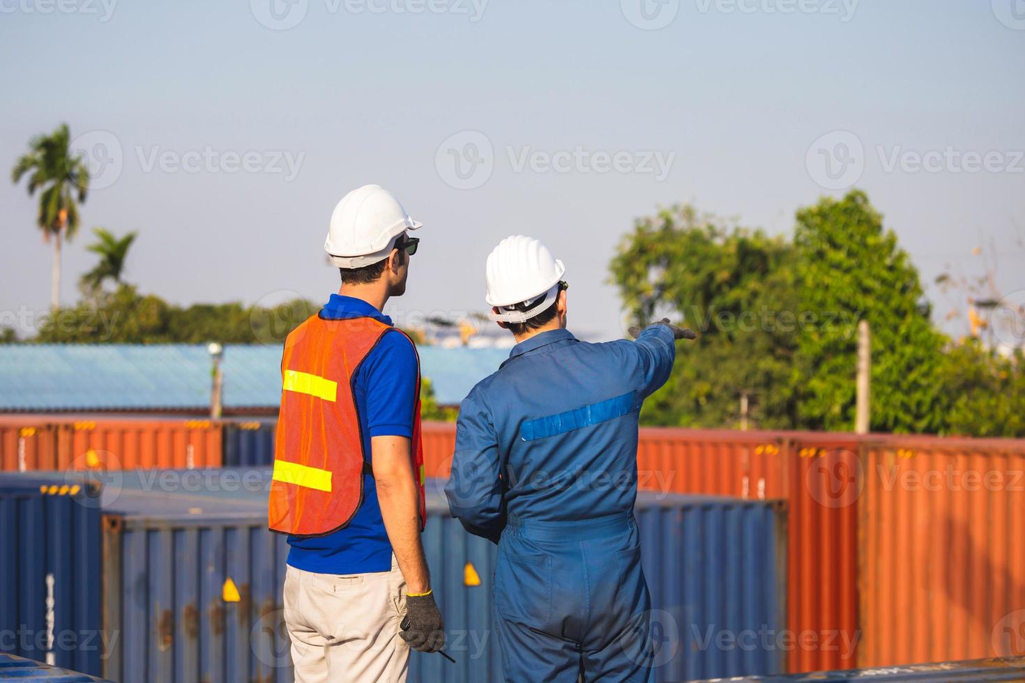 Worker man in hardhat and safety vest and foreman checking control loading containers box from cargo, Teamwork concepts photo
