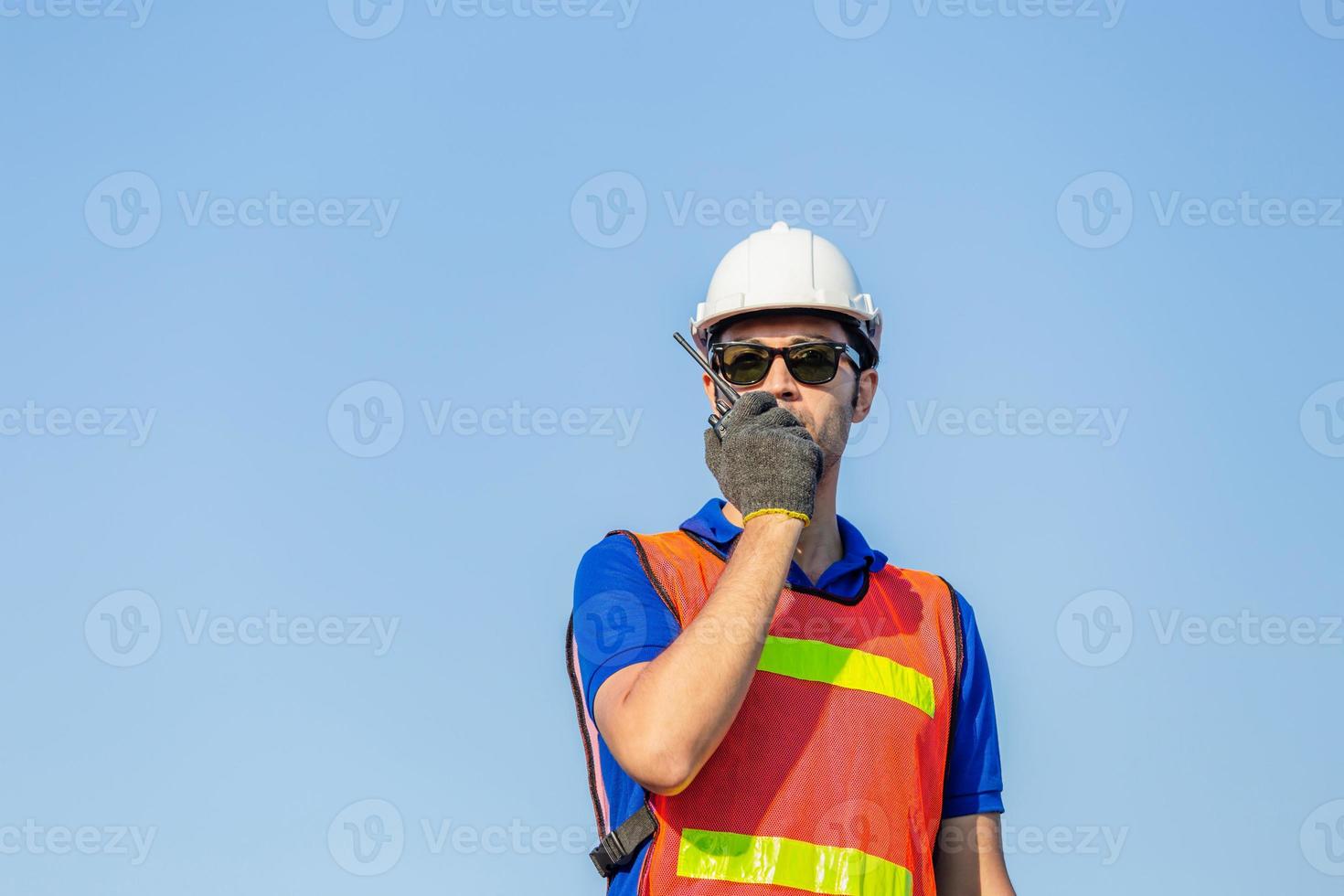 Foreman in hardhat and safety vest talks on two-way radio control loading containers box from cargo photo