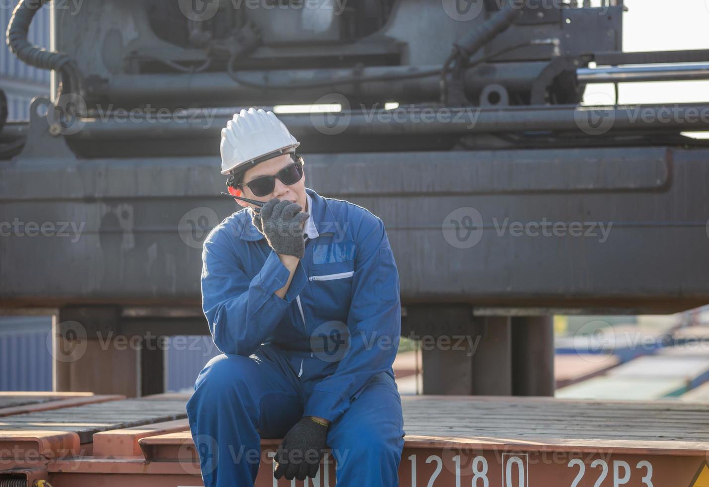 Foreman in hardhat and safety vest talks on two-way radio control loading containers box from cargo photo