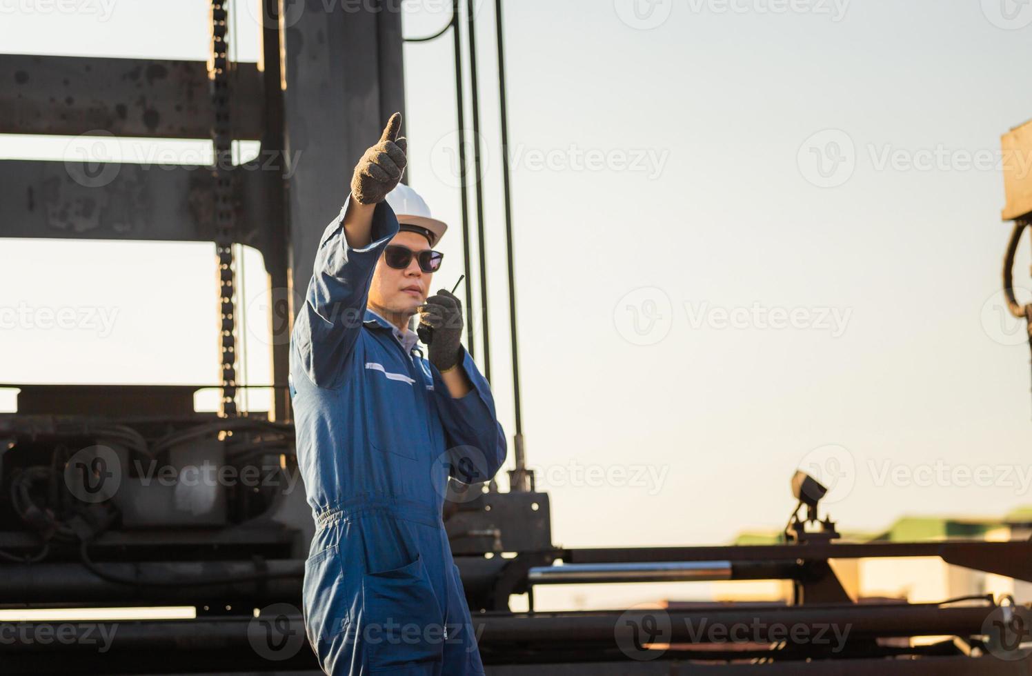 Foreman in hardhat and safety vest talks on two-way radio control loading containers box from cargo photo