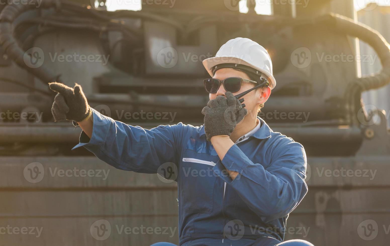 Factory worker man in hardhat and safety vest talks on two-way radio control loading containers box from cargo photo