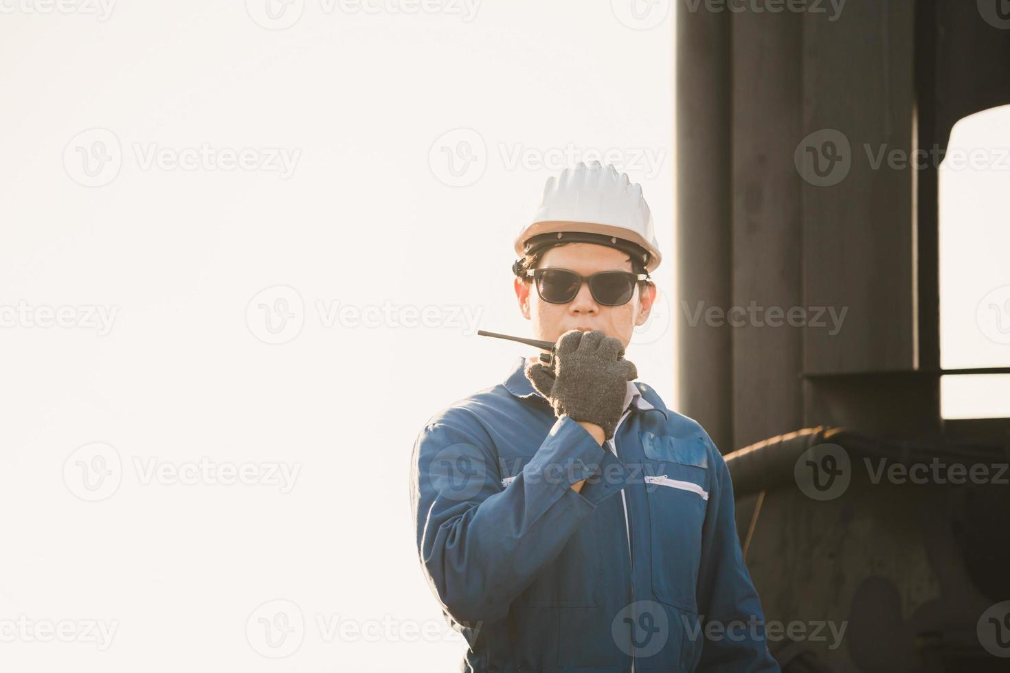 Foreman in hardhat and safety vest talks on two-way radio control loading containers box from cargo photo