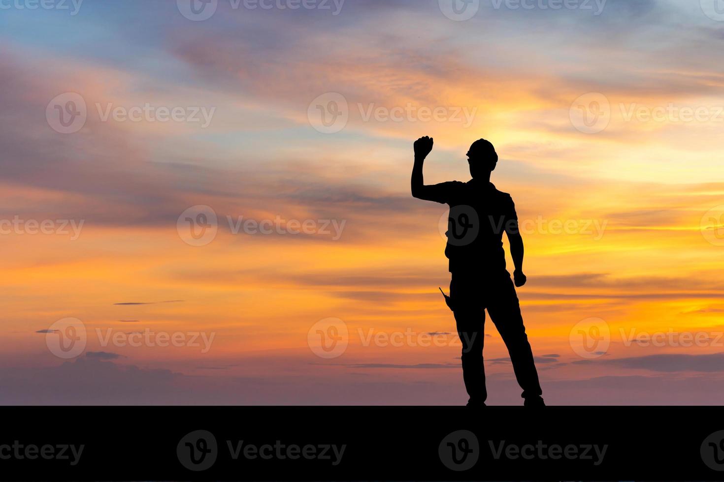 Silhouette of Factory worker man with clipping path in hard hat with celebrating victory, young man celebrates with hand in the air sunset background photo