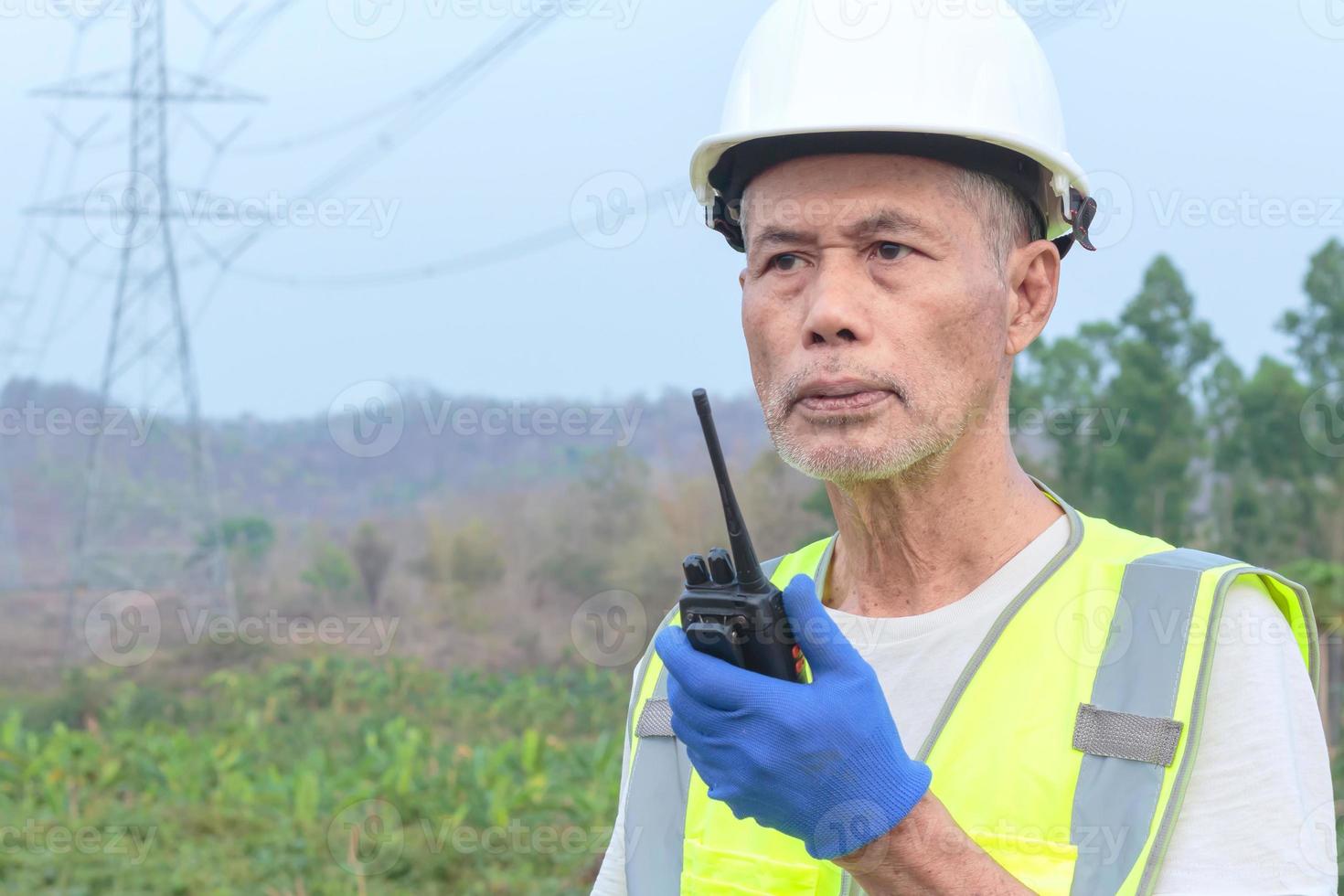 A senior engineer inspects a high-voltage power pole in a forested area. photo
