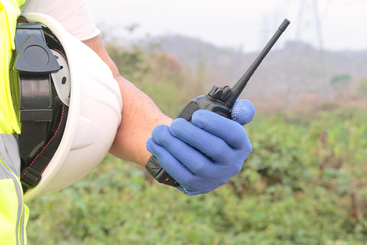 Hand holding a radio transmitter or the arm of an engineer or worker holding onto a white helmet. Prepare for work safety photo