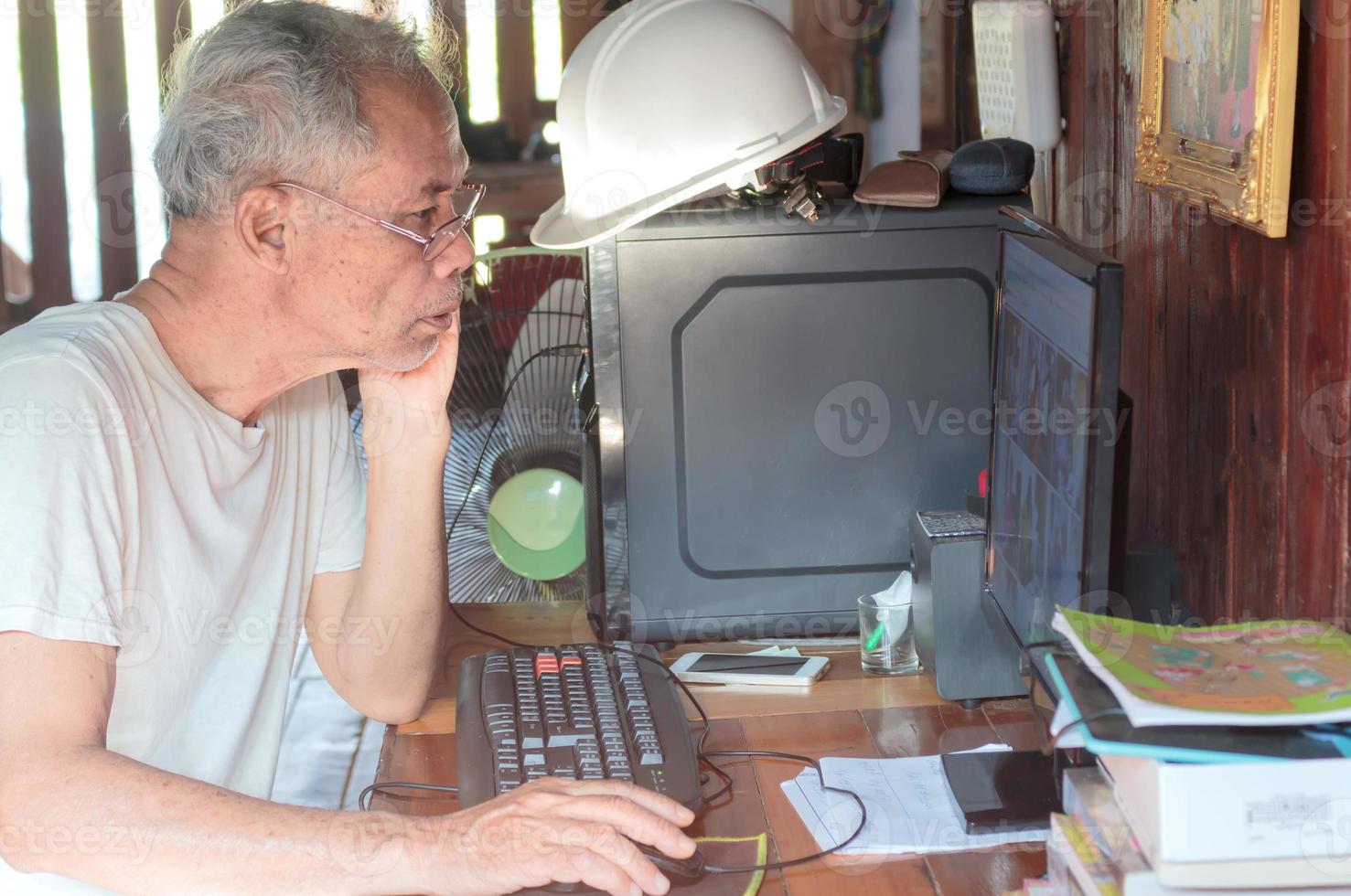 anciano asiático trabajando desde casa con computadora foto