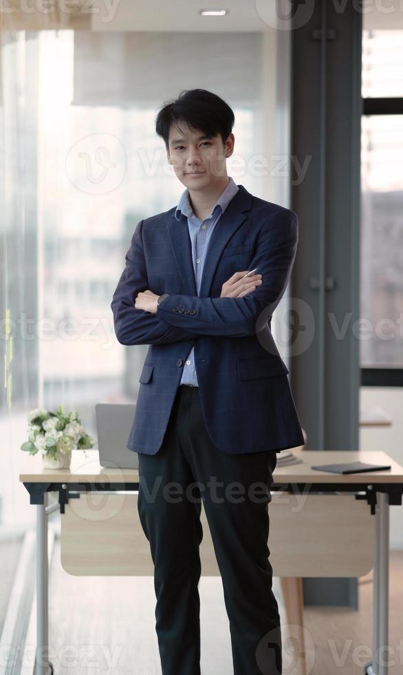 Young businessman standing at the office looking at the camera photo