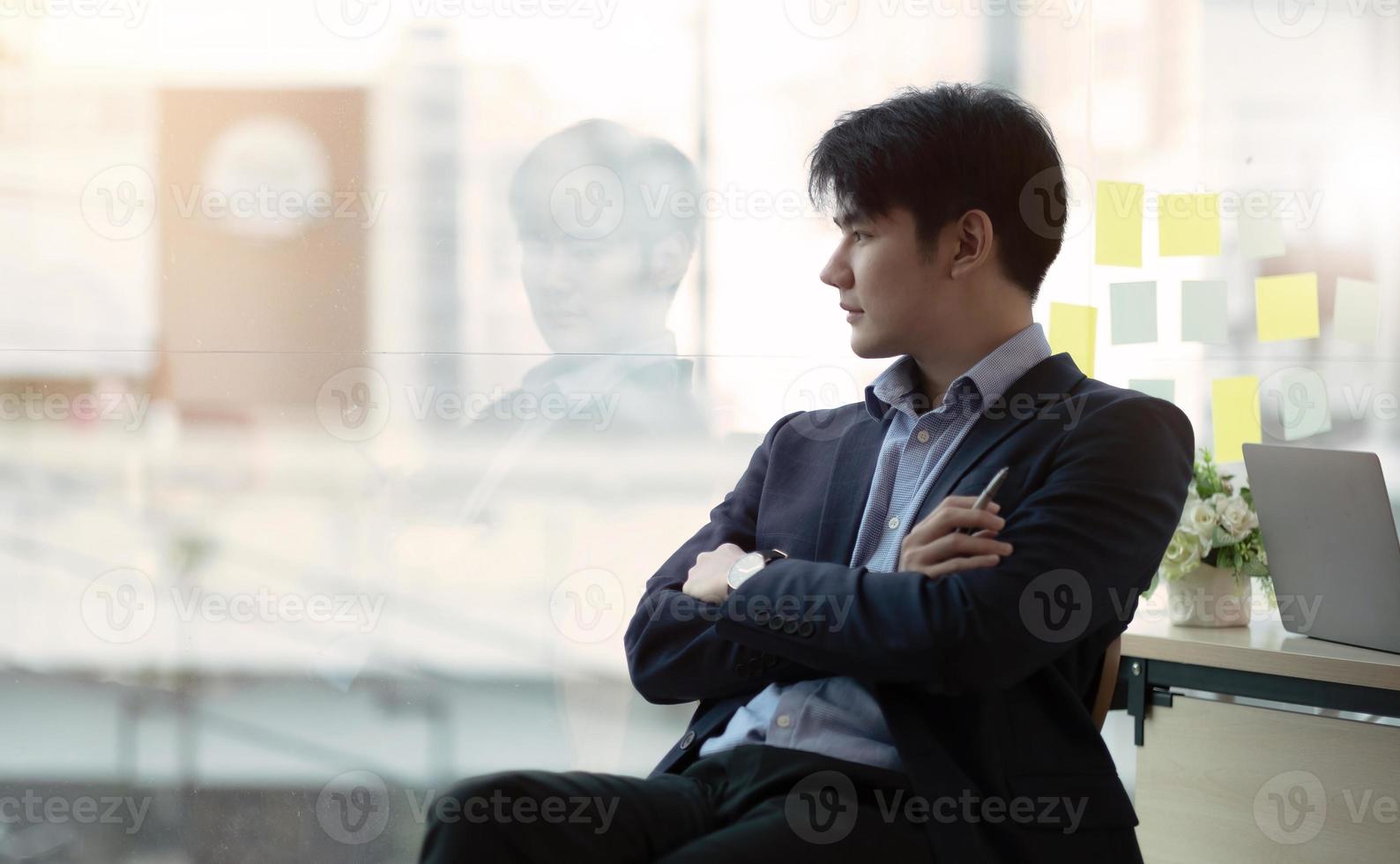 Charming asian businessman sitting working on laptop in office. photo