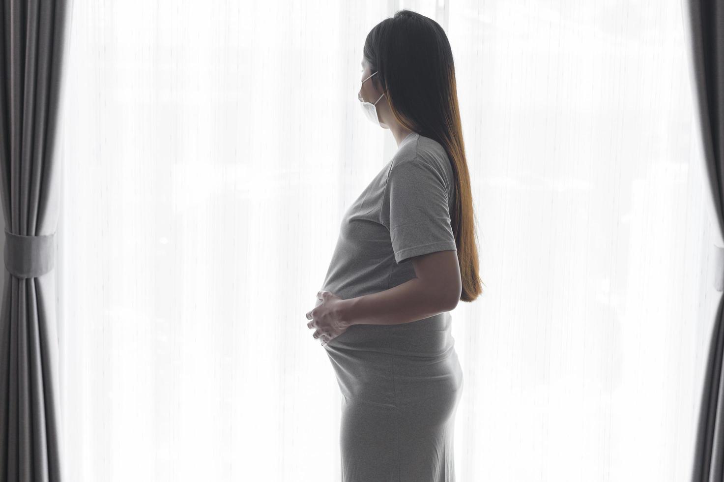 mujer embarazada joven con una máscara protectora y esperando un concepto de bebé, salud y maternidad foto