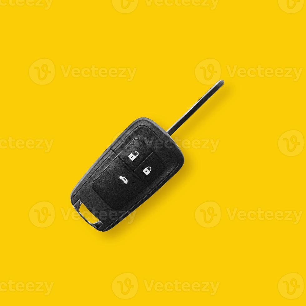 New black car key on yellow background with light shadow. photo
