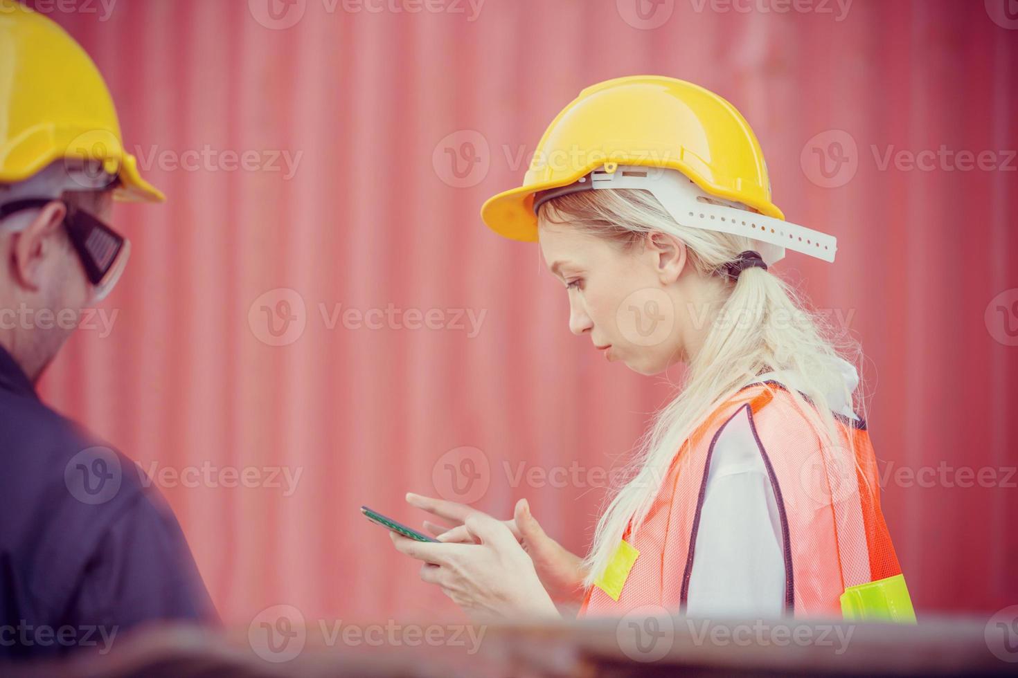 Female engineer in the hard hat uses mobile phone, Industrial worker using mobile smartphone in industry containers cargo photo