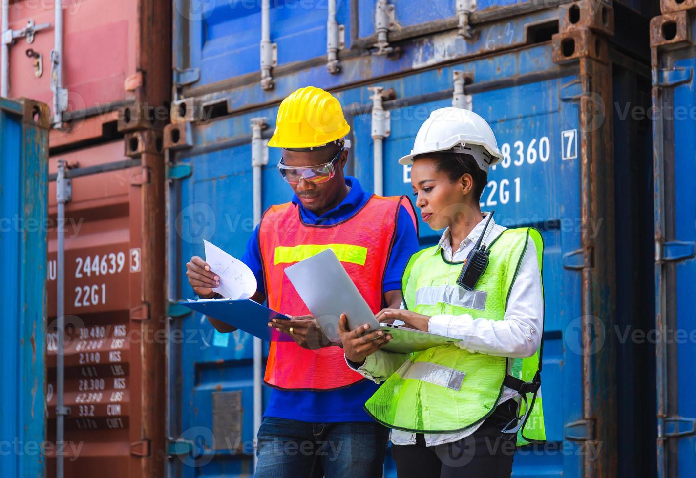 Happy worker man in hardhat and safety vest holding clipboard checklist and Female foreman using laptop control loading containers box from cargo photo