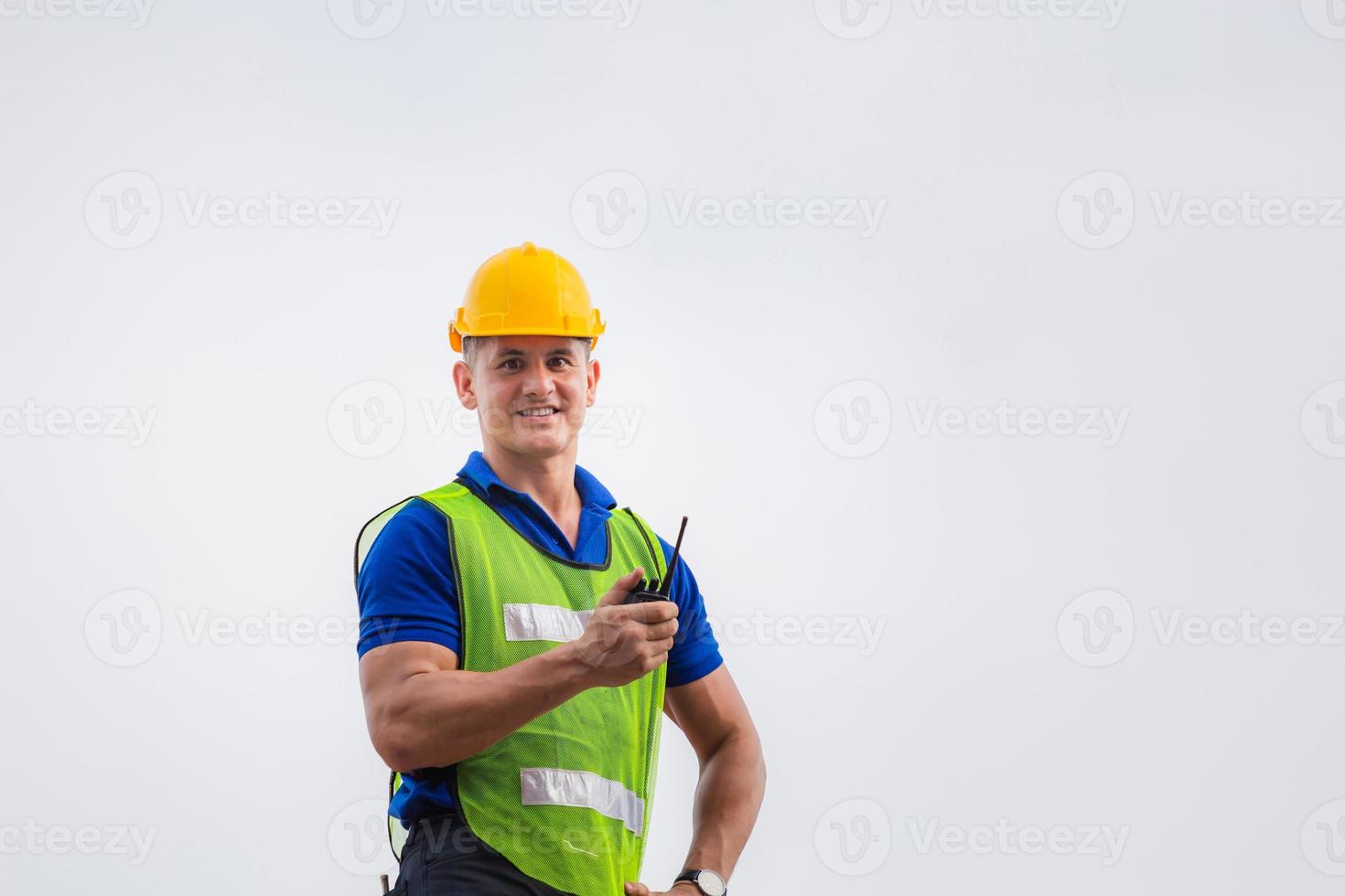 Foreman worker in hardhat and safety vest standing on container box holding two-way radio control and looking at camera photo