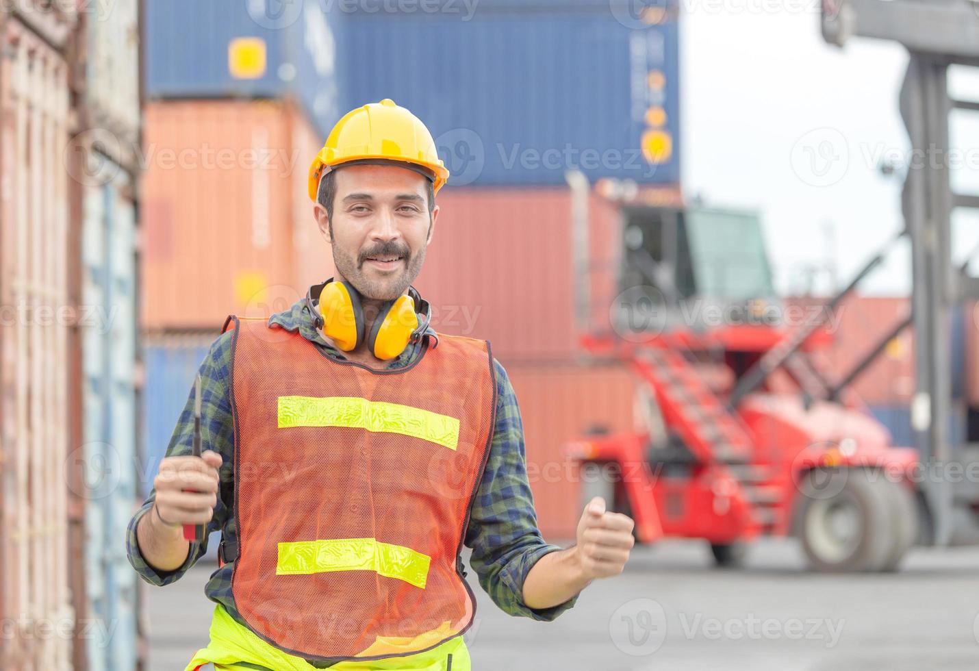 Cheerful engineer man in hard hat celebrating victory, foreman worker raise hands in celebration at container cargo photo
