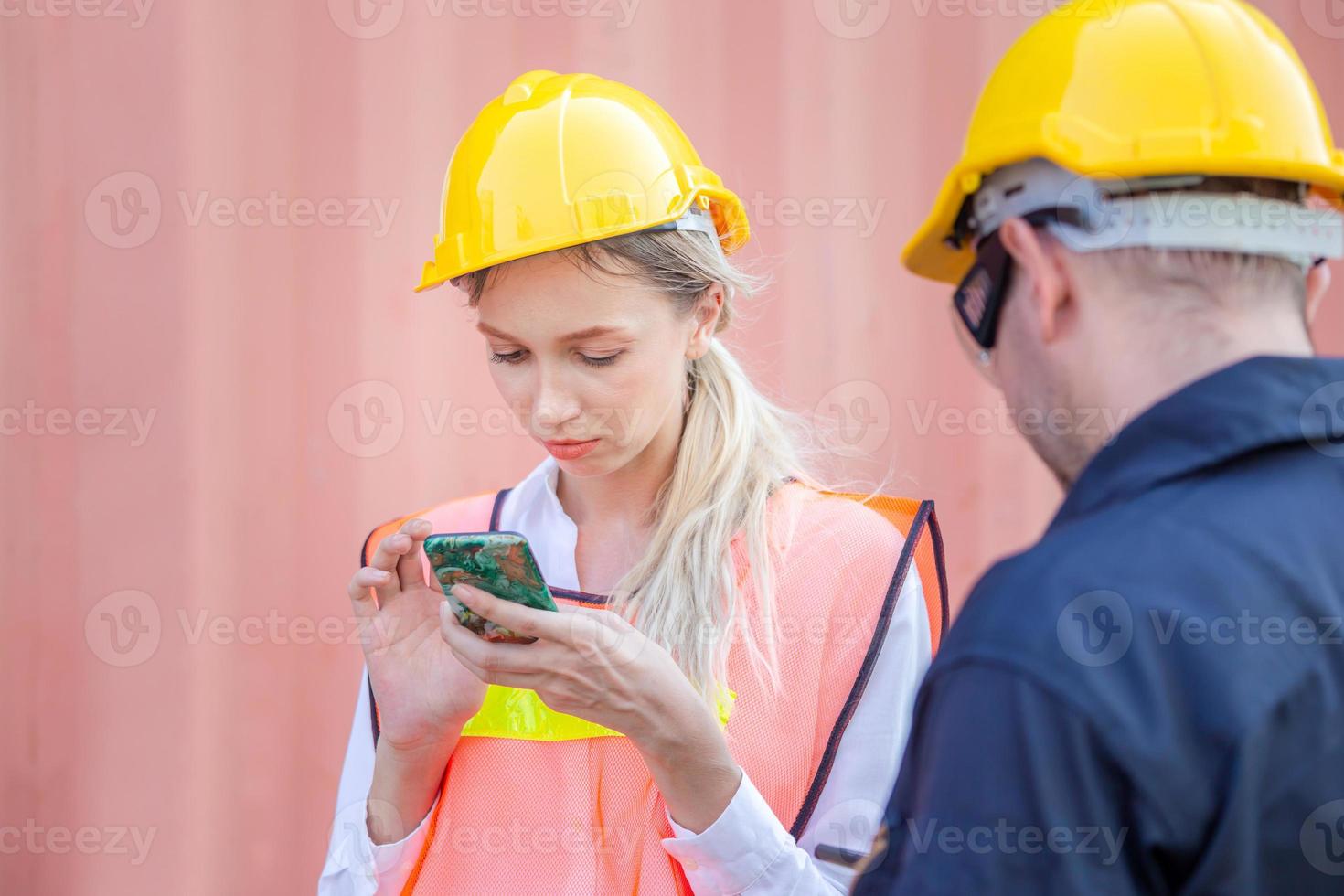 Engineer in the hard hat uses mobile phone, Industrial worker using mobile smartphone in industry containers cargo photo