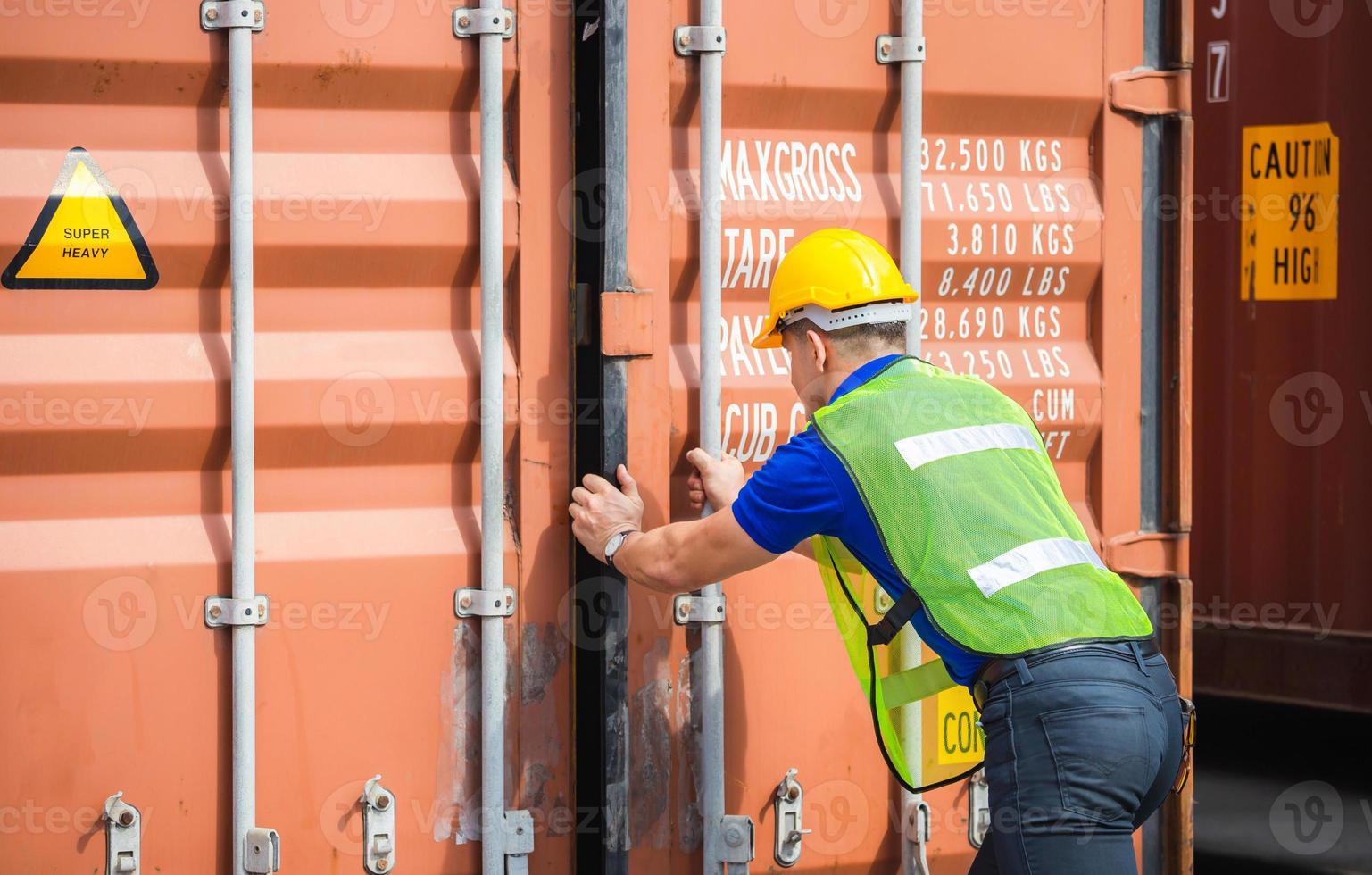 Engineer worker man in hardhat and safety vest checking containers box from cargo photo