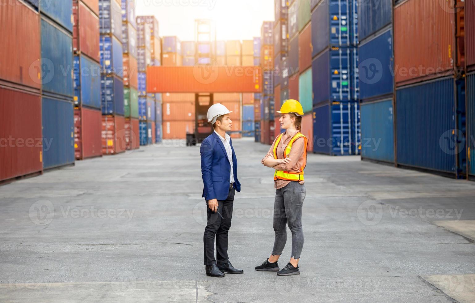 Engineer and foreman worker team in hardhat and safety vest control loading containers box from cargo photo
