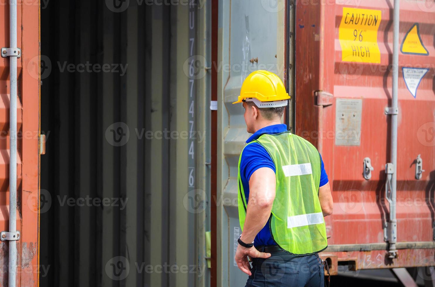 Engineer worker man in hardhat and safety vest checking containers box from cargo photo