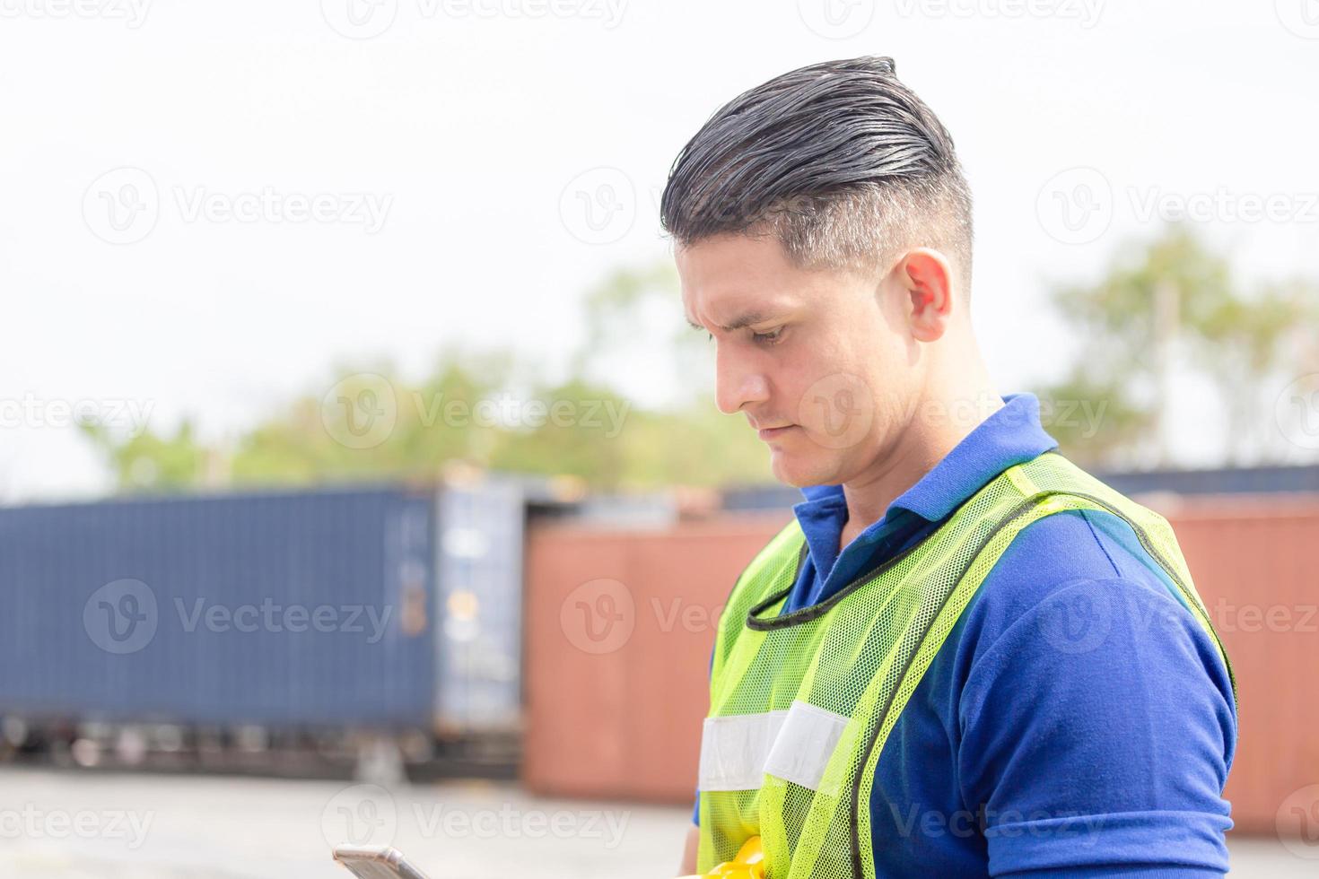 hombre ingeniero usa teléfono móvil, trabajador industrial usando teléfono inteligente móvil en contenedores de carga de la industria foto