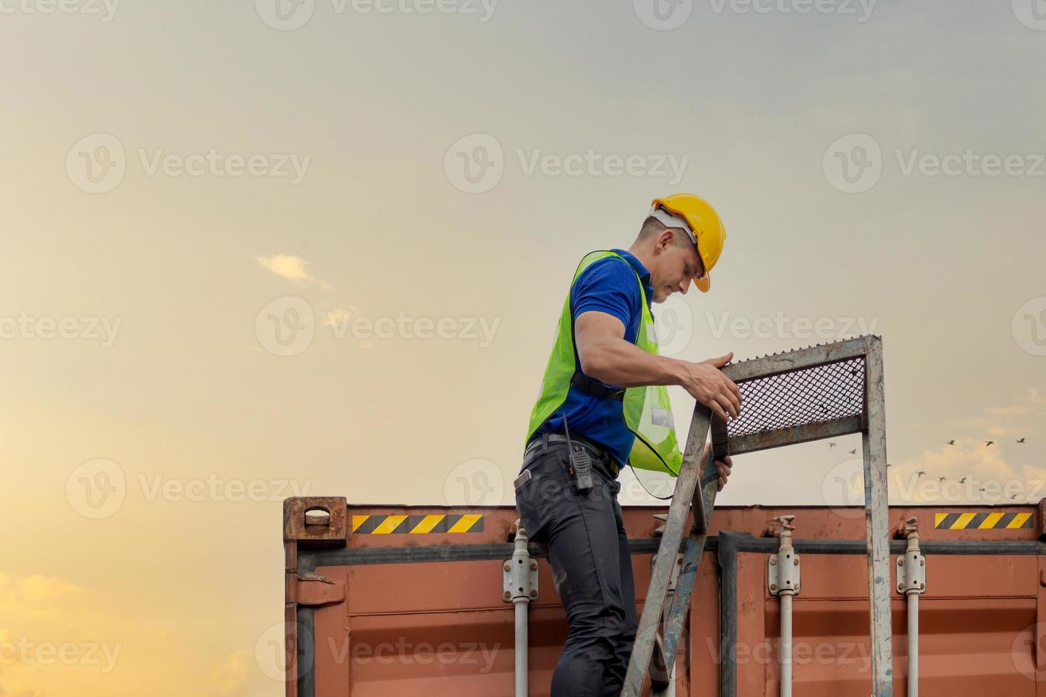 el trabajador sube la escalera hasta el contenedor, el ingeniero revisa la caja de contenedores de la carga foto