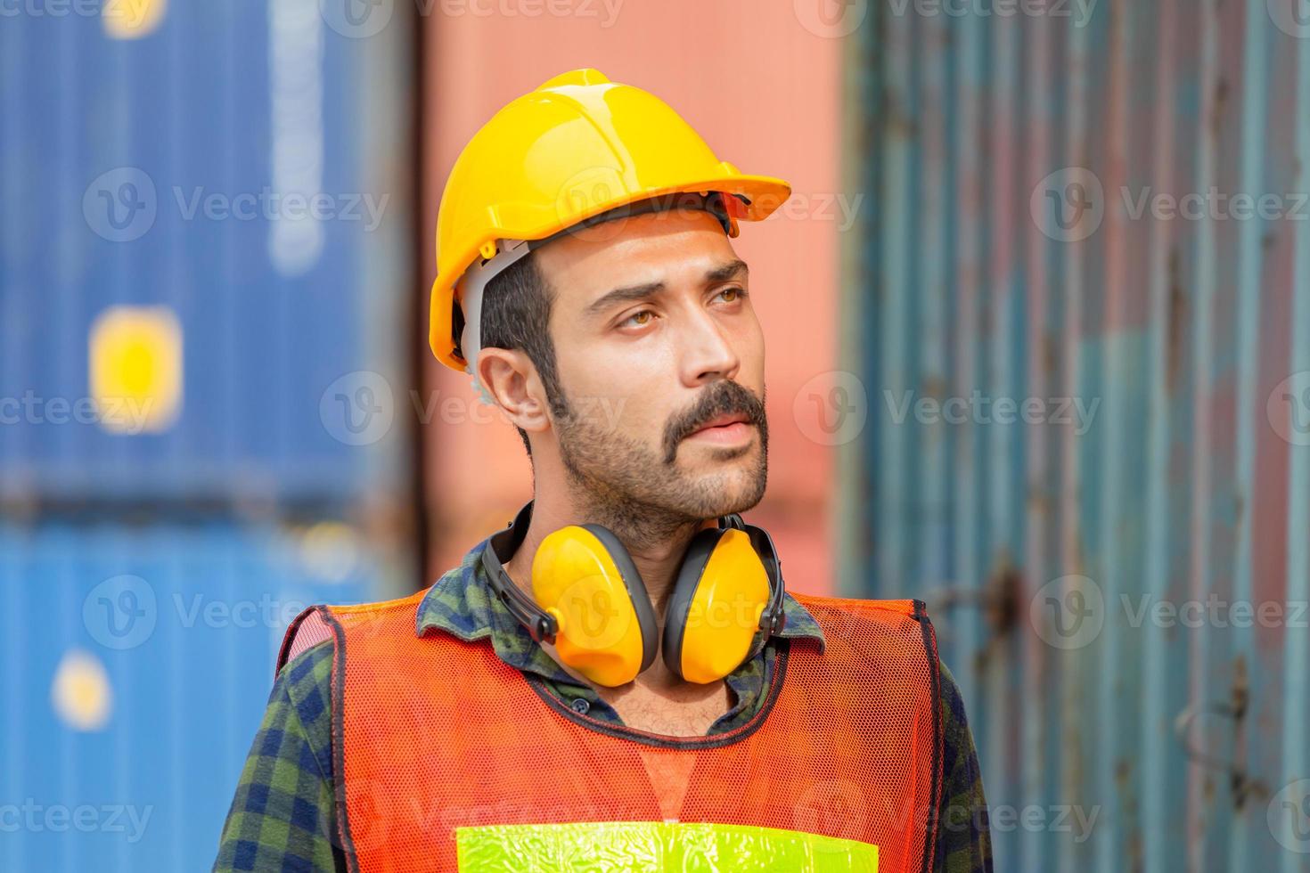 retrato de un trabajador de fábrica con casco y chaleco de seguridad, ingeniero con fondo de caja de contenedores en la carga foto