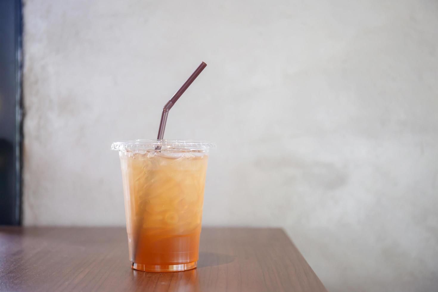 Peach ice tea in plastic cup on wooden table photo