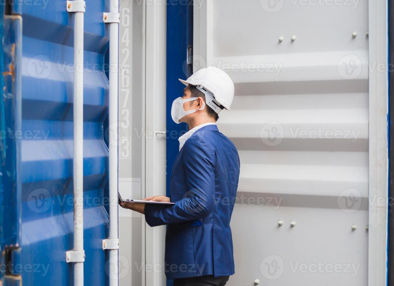Engineer wearing protection face mask against coronavirus, Foreman worker checking containers box from cargo photo