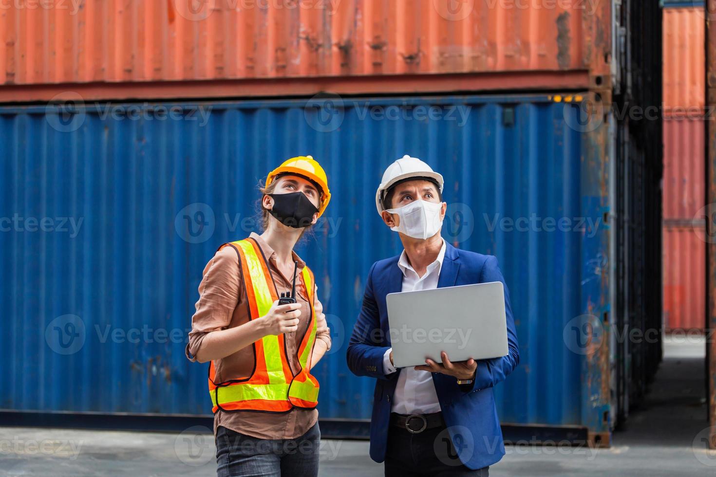 Engineer and worker team wearing protection face mask against coronavirus checking containers box from cargo, Logistic and teamwork concept photo