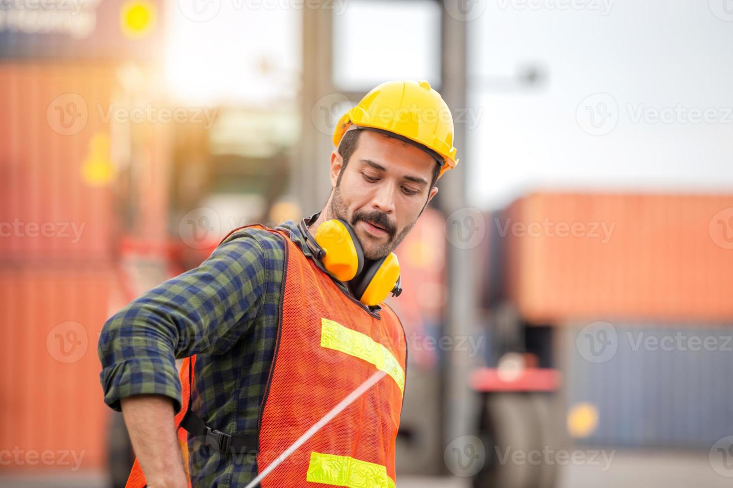 Funny factory worker man in hard hat and safety vest, Happiness engineer at cargo containers concept photo