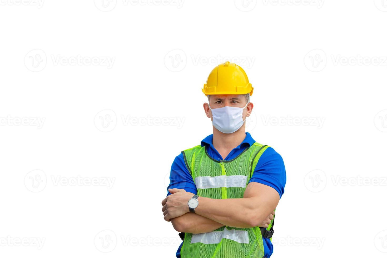 Cheerful engineer man in hard hat with clipping path wearing protection face mask against coronavirus with arms crossed on white background photo