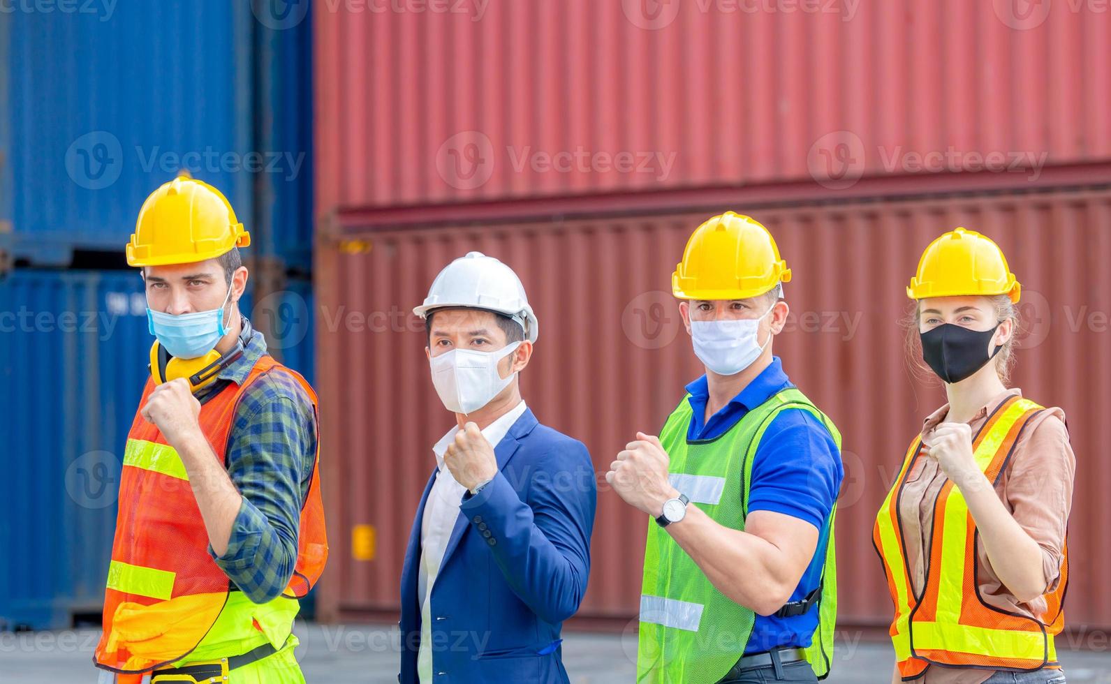 concepto de éxito y trabajo en equipo, equipo de ingenieros y trabajadores con mascarilla de protección contra el coronavirus, celebración del equipo de gente de negocios feliz con fondo de contenedores de carga borrosos foto