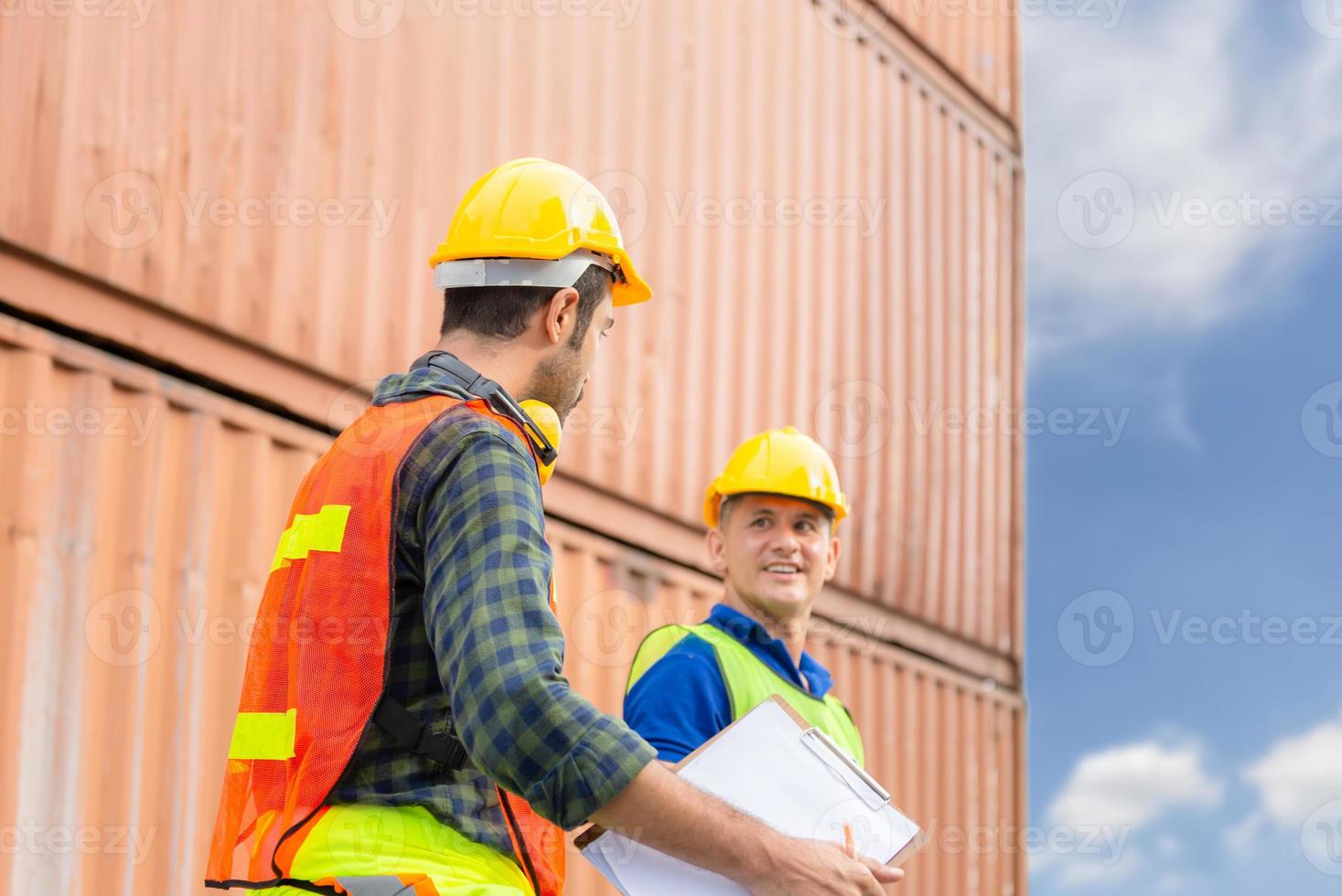 ingeniero feliz y equipo de trabajadores revisando la caja de contenedores de carga con fondo borroso, concepto de trabajo en equipo foto