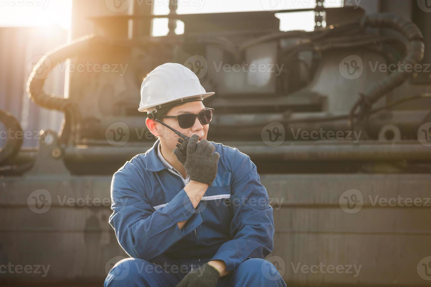 Foreman in hardhat and safety vest talks on two-way radio control loading containers box from cargo photo