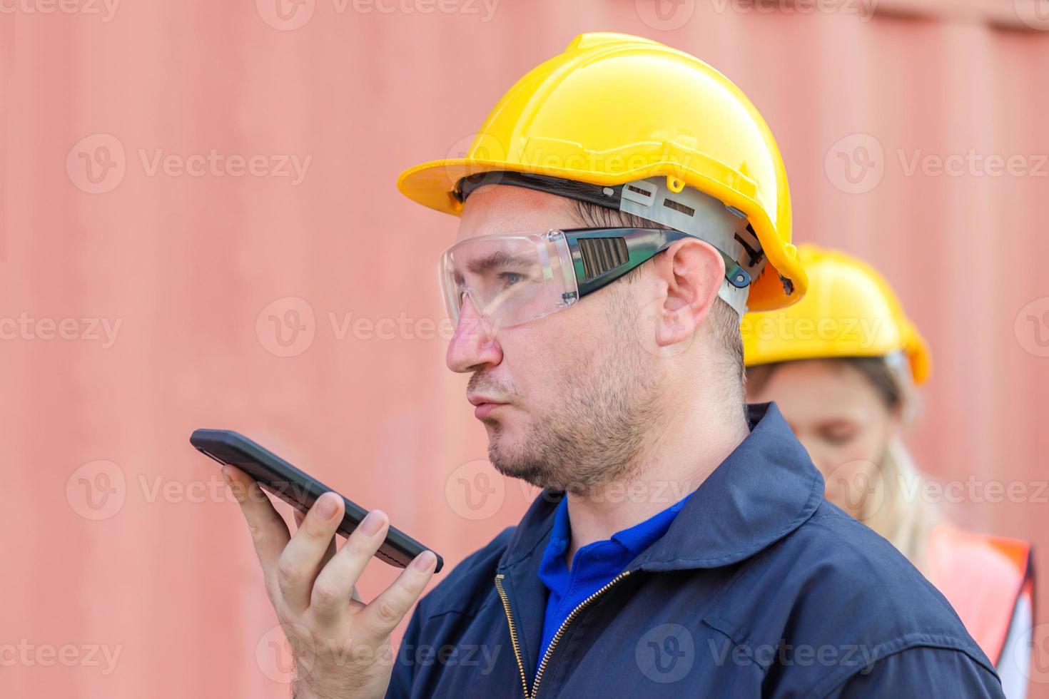 Engineer in the hard hat uses mobile phone, Industrial worker using mobile smartphone in industry containers cargo photo