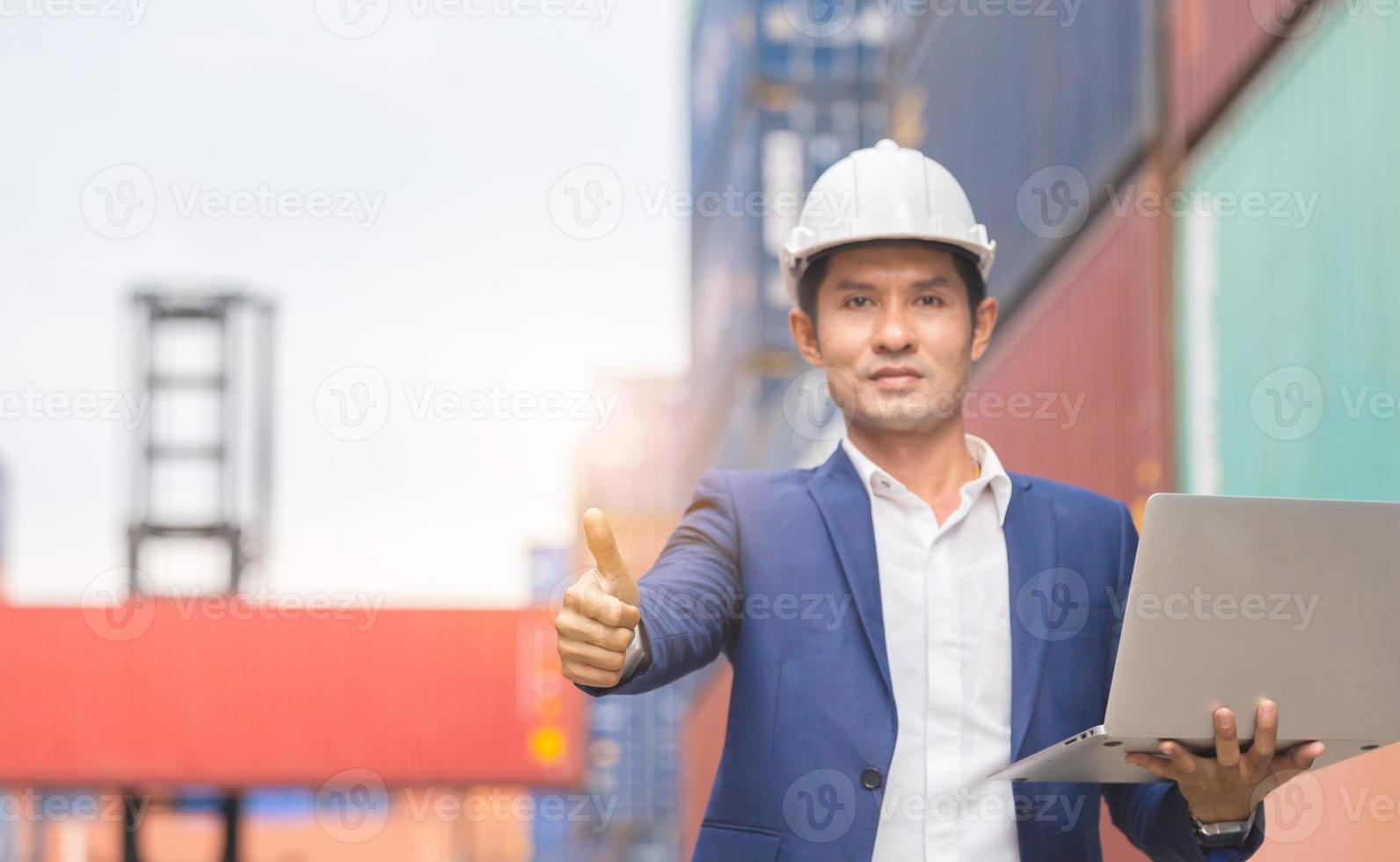 Cheerful engineer man holding laptop with giving thumbs up as sign of success photo