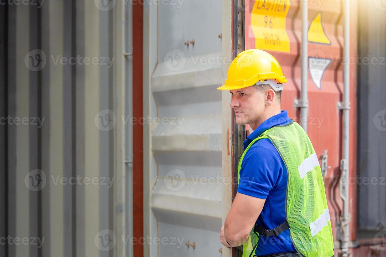 Foreman worker in hard hat and safety vest checking containers box from cargo photo