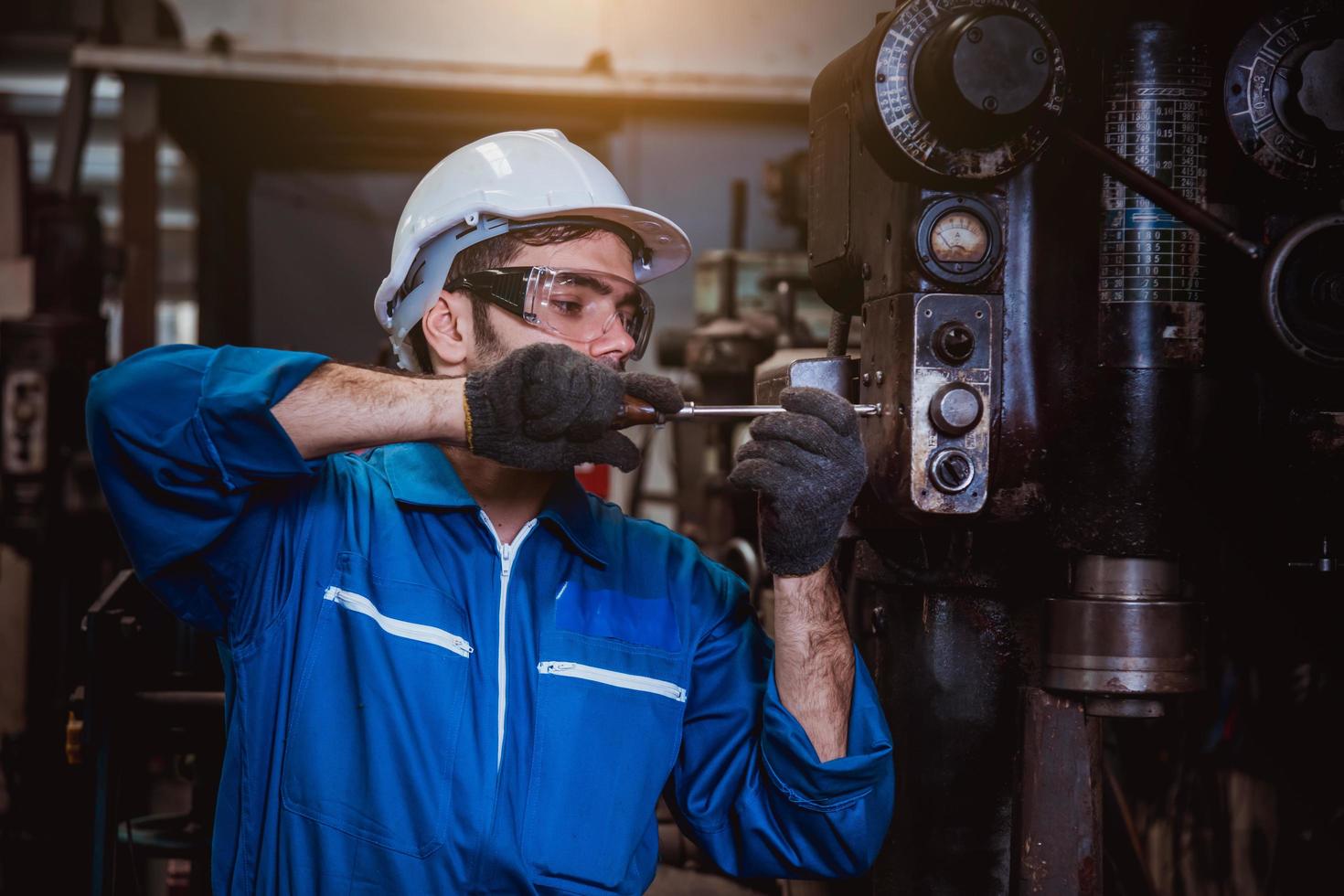 ingeniería industrial con control uniforme de seguridad que opera la máquina rectificadora de torno que trabaja en la fábrica de la industria. foto