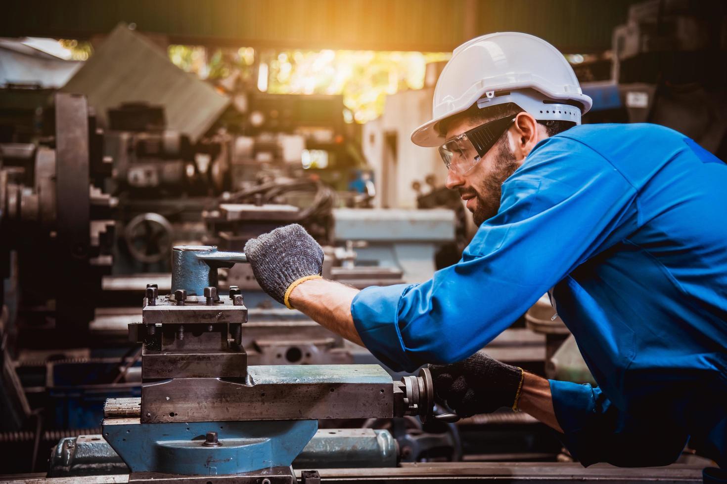 ingeniería industrial con control uniforme de seguridad que opera la máquina rectificadora de torno que trabaja en la fábrica de la industria. foto