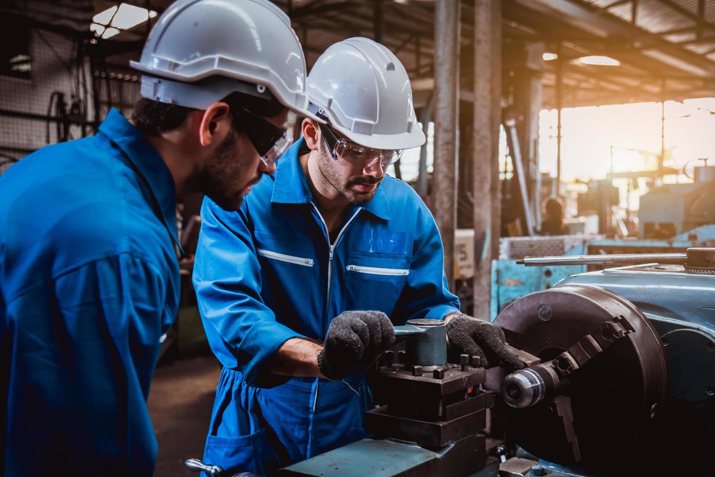 ingeniería industrial con control uniforme de seguridad que opera la máquina rectificadora de torno que trabaja en la fábrica de la industria. foto