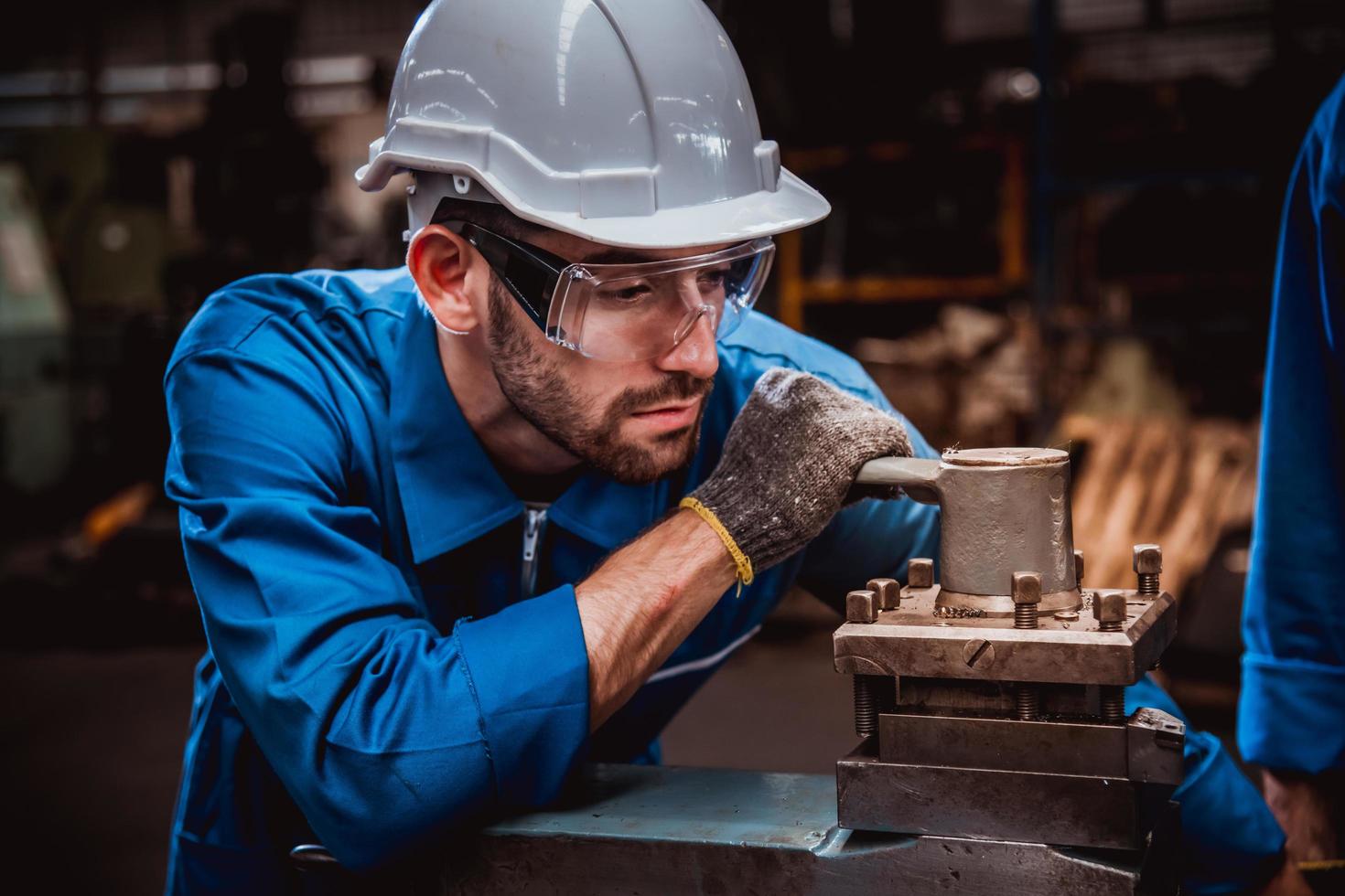 ingeniería industrial con control uniforme de seguridad que opera la máquina rectificadora de torno que trabaja en la fábrica de la industria. foto