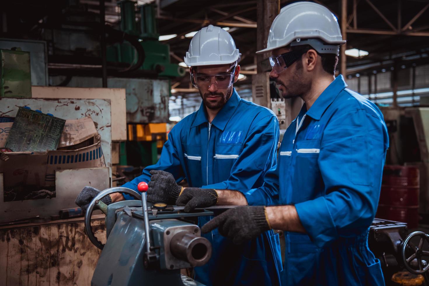 ingeniería industrial con control uniforme de seguridad que opera la máquina rectificadora de torno controlada por computadora que trabaja en la fábrica de la industria. foto