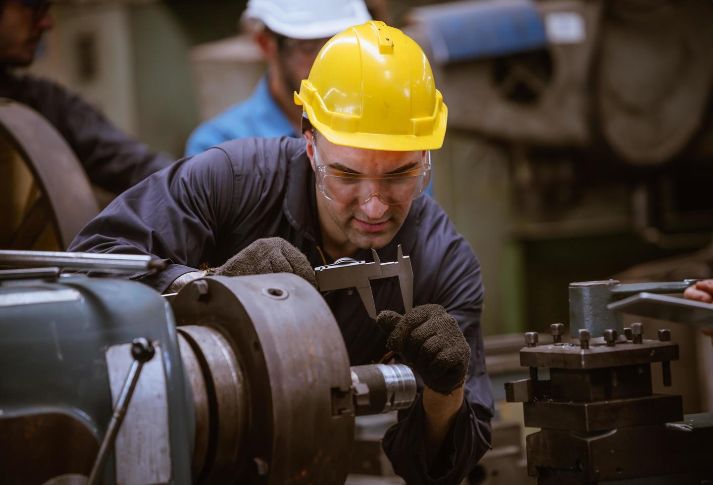 ingeniería industrial con control uniforme de seguridad que opera la máquina rectificadora de torno controlada por computadora que trabaja en la fábrica de la industria. foto