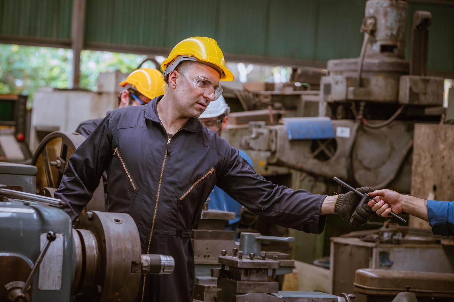 ingeniería industrial con control uniforme de seguridad que opera la máquina rectificadora de torno controlada por computadora que trabaja en la fábrica de la industria. foto