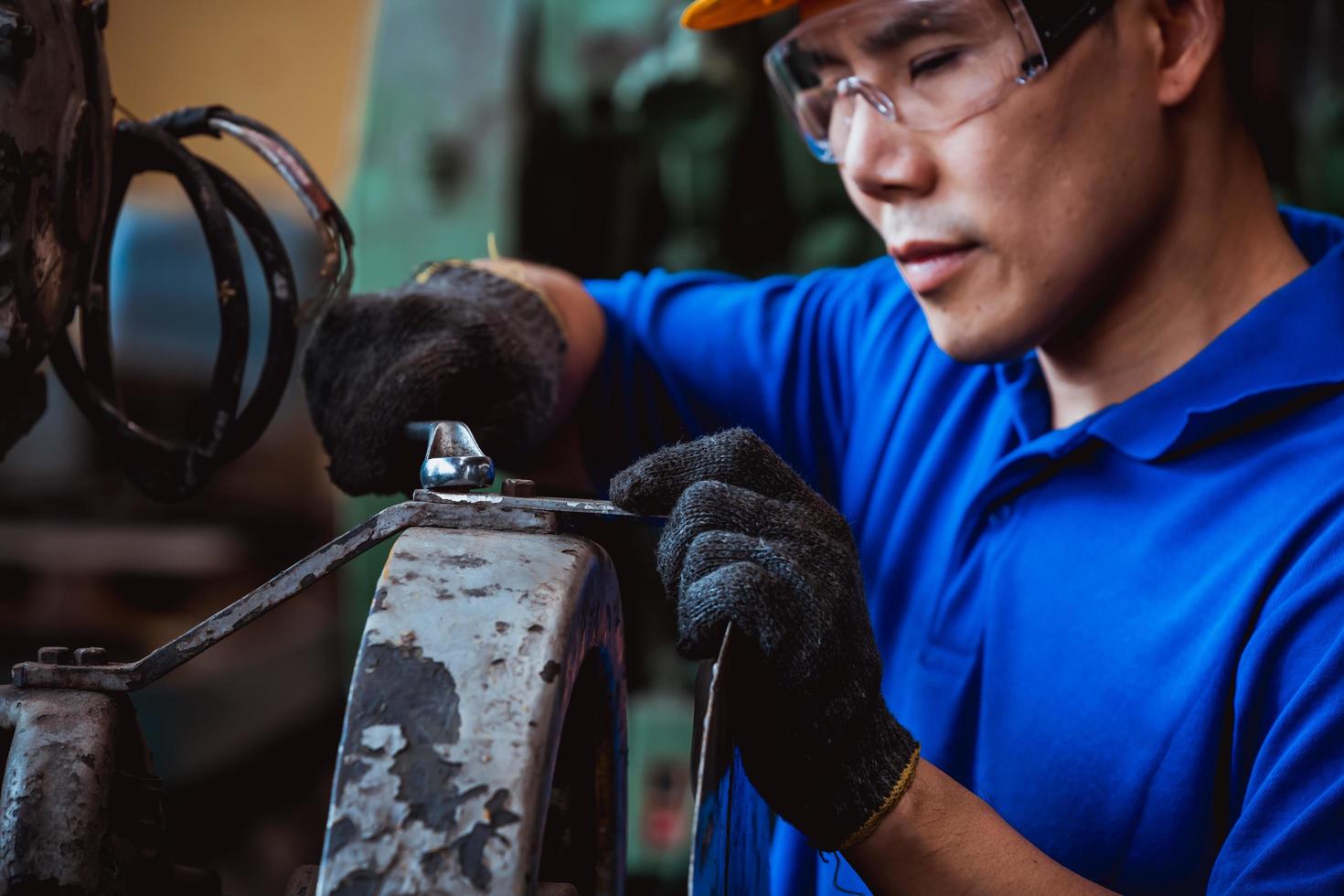 ingeniería industrial con control uniforme de seguridad que opera la máquina rectificadora de torno controlada por computadora que trabaja en la fábrica de la industria. foto